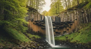 Cascade dévalant une paroi d'orgues basaltiques dans une vallée glaciaire du Cantal au printemps