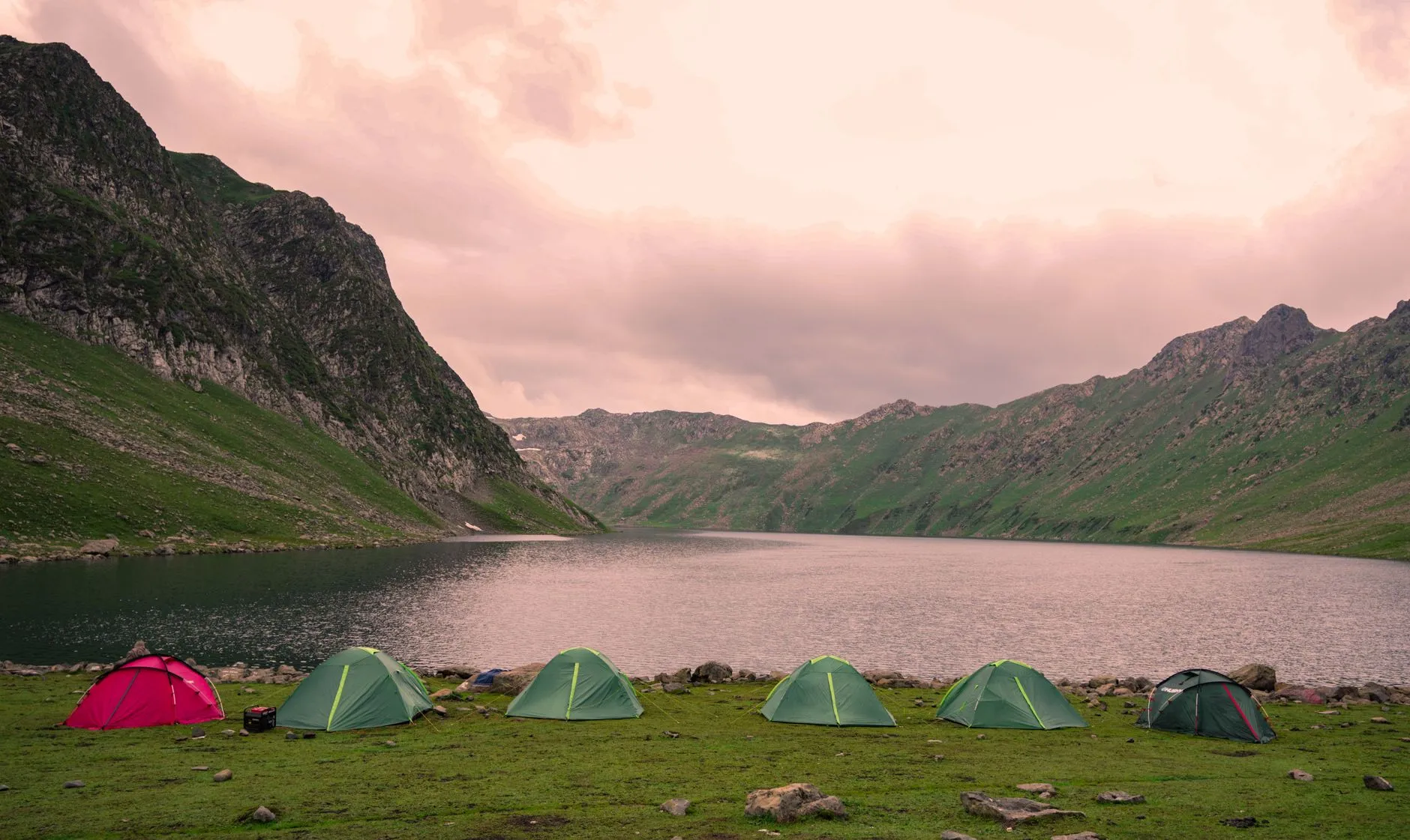 Emplacements de camping au bord d'un lac de barrage dans le Cantal, avec les collines volcaniques en arrière-plan